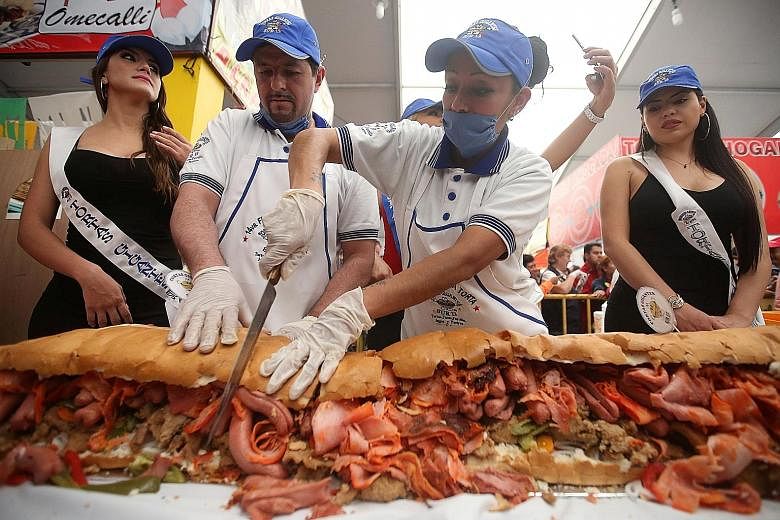 A cook cutting a 67m-long, 820kg torta sandwich in Mexico City.