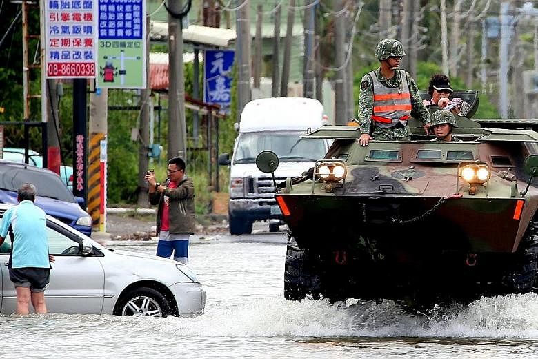 Soldiers on their way to deliver food and water to people stranded in flood-hit areas in Pingtung, southern Taiwan, yesterday.