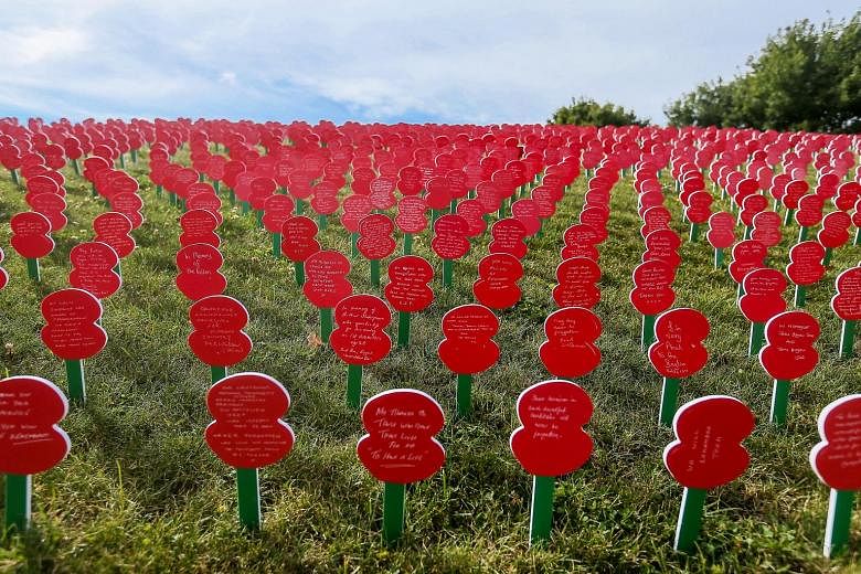Cut-out poppies with messages dedicated to the soldiers who fell during World War I written on them, on the lawn at the Tyne Cot Commonwealth War Graves Cemetery in Zonnebeke, Belgium. It is as part of a series of commemorations for the 100th anniver
