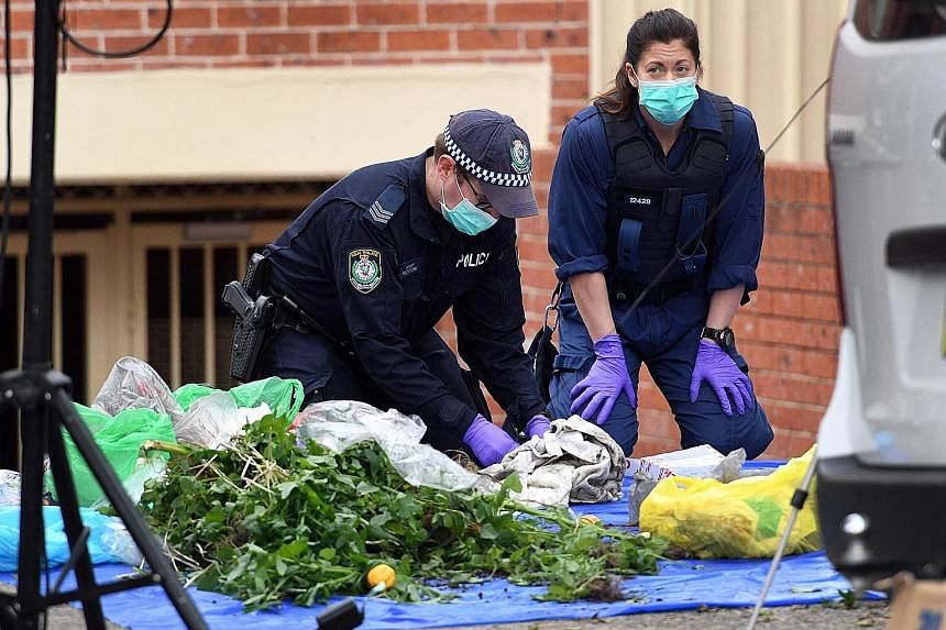Police searching for evidence at a block of flats in the Sydney suburb of Lakemba yesterday. They found a flight number for a Jakarta to Sydney flight in a bin, but it was not clear if this flight was being targeted.