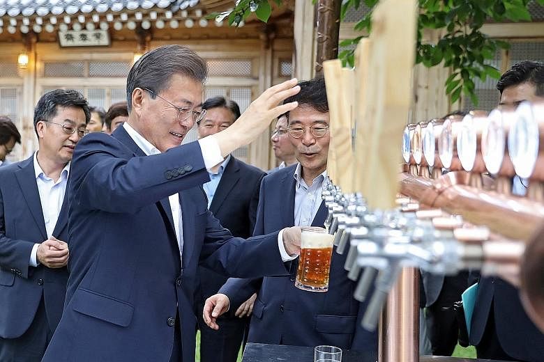Mr Moon Jae In pouring himself a glass of beer during a meeting with business leaders in Seoul last week. His policy of listening to the people has helped him maintain a high approval rating. A recent poll showed 74 per cent approved of his managemen