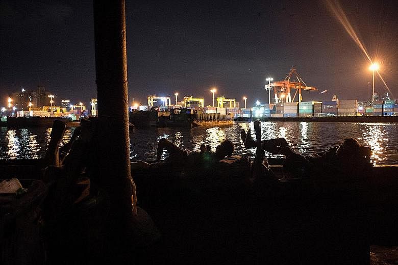 People kicking back amid activity going on in the port area of Manila Bay. Singapore firms have invested in port operations, ship-building and hotels in the Philippines.