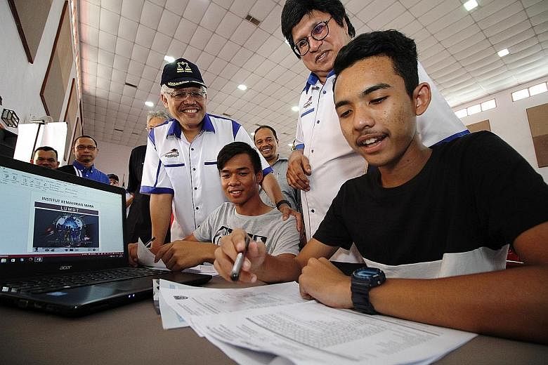 Domestic Trade, Cooperatives and Consumerism Minister Hamzah Zainudin (in cap) and Bumiputera Education Tour main committee chairman Sahol Hamid Abu Bakar observing as students in Perak apply for college. Under Malaysia's affirmative action New Econo