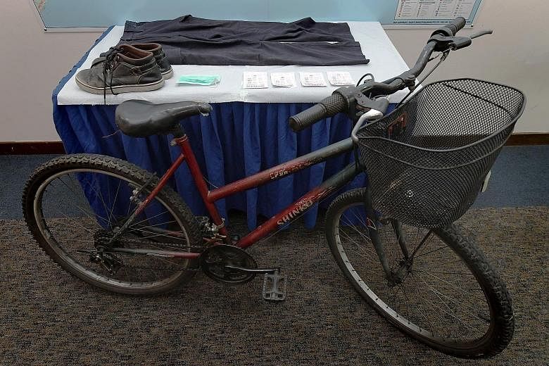 Items recovered by the police included the getaway bike, 4D tickets bought by the suspect and his shoes. The suspect at the Western Union branch (right) in Ubi on Tuesday. He was arrested in Pasir Ris after a three-day manhunt.