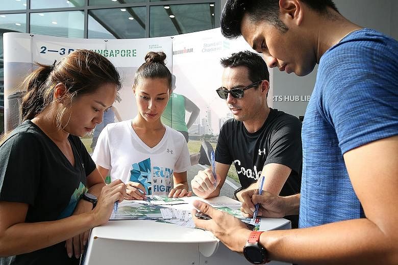 Under Armour Ambassadors Yang Man Yun (far left), Denise Keller (2nd from left) and SCSM Ambassador Joakim Gomez (right) getting zoning advice from running coach Ben Pulham.