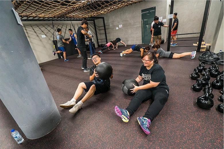 Christine Lim (right) and her husband Wallace Tan working out with medicine balls during the Polar Fitness Bootcamp at TripleFit.
