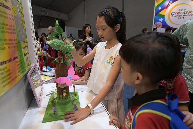 Above: Kong Hwa School pupil Goh Chen Yu, who won the second prize in the Whizkid category of the Sony Creative Science Award, with her project, "Where Has My Caterpillar Gone?" Left: Rulang Primary School pupils Nicole Tan (wearing red tie) and Rach