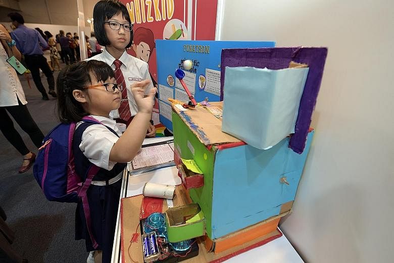 Above: Kong Hwa School pupil Goh Chen Yu, who won the second prize in the Whizkid category of the Sony Creative Science Award, with her project, "Where Has My Caterpillar Gone?" Left: Rulang Primary School pupils Nicole Tan (wearing red tie) and Rach