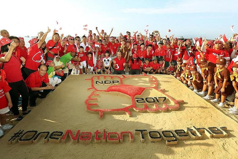 Together with over 800 Bedok residents and students, Mr Lim Swee Say unveiled the sand art sculpture, which depicts this year's National Day Parade logo, at East Coast Park yesterday morning.