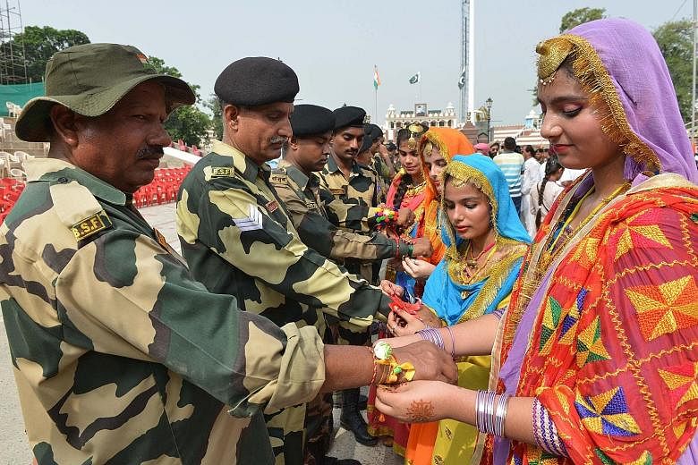 Indian schoolgirls tying sacred thread, or rakhi, onto the wrists of soldiers from the Indian Border Security Force during a ceremony observing the festival of Raksha Bandhan at the India-Pakistan Wagah border post about 35km from Amritsar, in the no