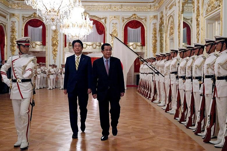 Cambodian Prime Minister Hun Sen (right) reviewing the guard of honour with Japanese Premier Shinzo Abe during a welcoming ceremony at the State Guest House in Tokyo yesterday.