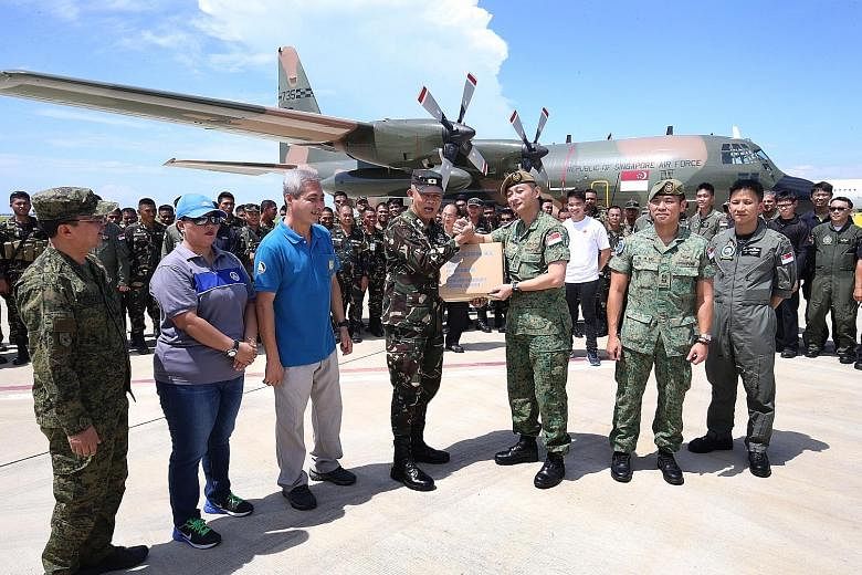 Brigadier-General Cristobal Zaragosa, assistant division commander of the 4th Infantry Division in the Armed Forces of the Philippines, receiving aid supplies from Singapore Armed Forces (SAF) Colonel Lee Kuan Chung, director of the Changi Regional H