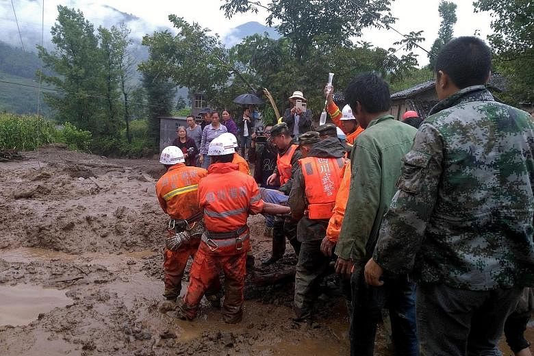 Rescue workers evacuating a man injured during a landslide at Gengdi village, in Puge county in China's Sichuan province, yesterday. The landslide resulted in the deaths of at least 23 people and destroyed more than 70 homes. Two people were still mi