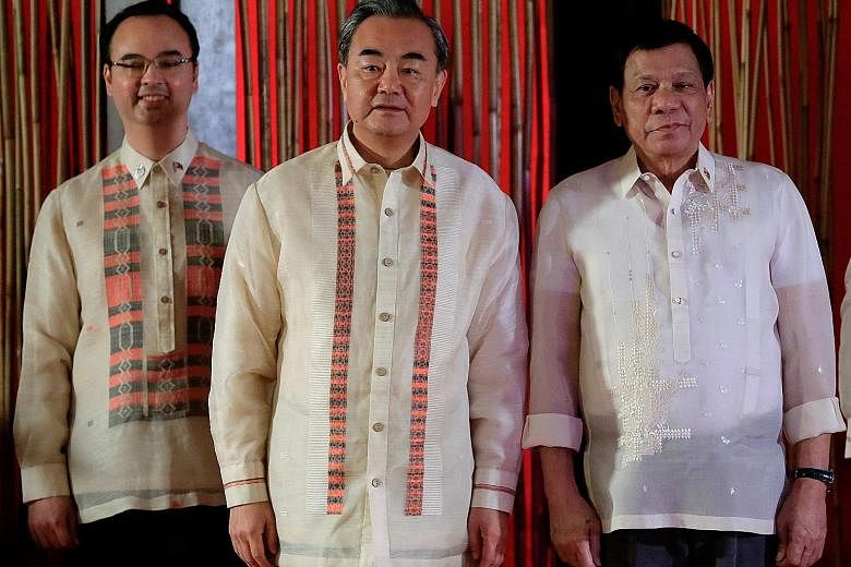 Philippine President Rodrigo Duterte with his Foreign Secretary Alan Cayetano (far left) and Chinese Foreign Minister Wang Yi. Mr Cayetano said China set aside its insistence on a "non-legally binding" code of conduct on maritime disputes in the Sout