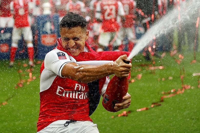 Alexis Sanchez celebrating Arsenal's FA Cup triumph last May. He will not be available for the first two league games of the season, having suffered an abdominal strain. The forward, whose contract expires next year, could move before the transfer wi
