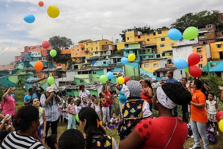 Residents of El Pesebre, a shanty town on the outskirts of Medellin in Colombia, celebrating French street artist Tarik Bouanani's art project on Wednesday. With the help of residents, Bouanani turned the 230 brick houses in the town into a giant mur