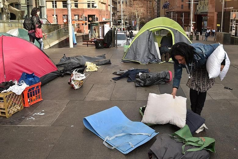 A homeless woman packing up her belongings in Martin Place, which had become known as "tent city", in the central business district of Sydney yesterday. The camp had become the most visible symbol of the lack of low-cost accommodation in Sydney.