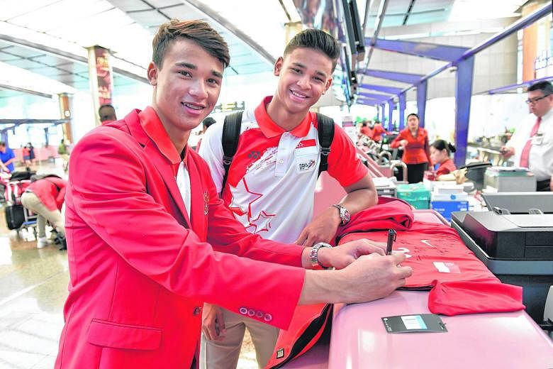 Ikhsan, 18, and Irfan Fandi (right), 20, sons of Singapore football legend Fandi Ahmad, autographing a jersey at Changi Airport before departing for the SEA Games yesterday afternoon. The football squad comprising Under-22 players were among the firs
