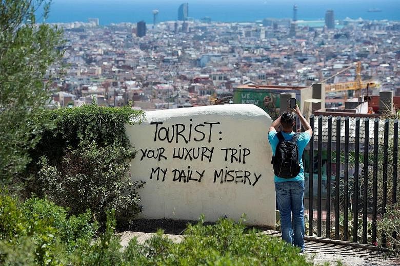 Ignoring the "less than friendly" graffiti, a tourist is focused on snapping a photo of Barcelona on Thursday.
