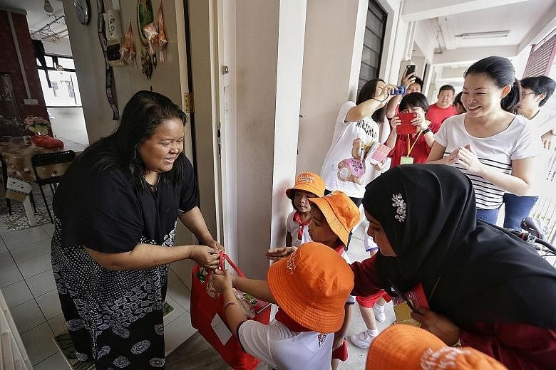 PCF Sparkletots pre-schoolers, accompanied by Tampines GRC MP Cheng Li Hui, giving a bag of provisions to housewife Julianah Sani, 41, yesterday.