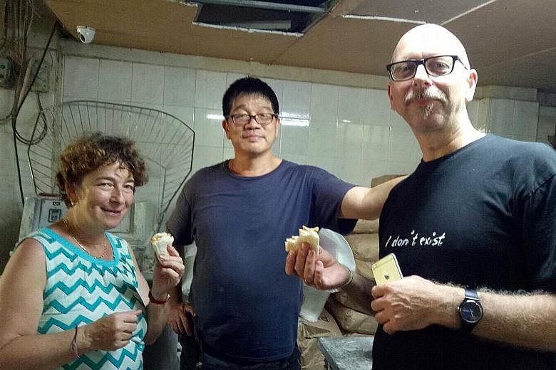 Above: Swiss tourists Gisela Aeschbach and Fredy Diener at Jie Bakery, with owner Jimmy Mah, as part of Tribe's Disappearing Trades tour. Right: Tribe co-founder Jason Loe with Mr Mah, who enjoys opening up his bakery to visitors as he has many stori
