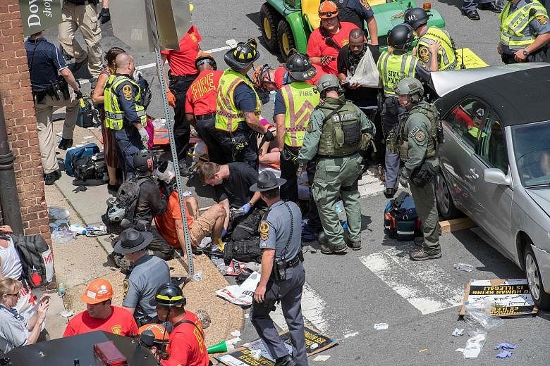 People receiving first aid after a car ploughed into a crowd of anti-fascist protesters fighting against white nationalists at a "Unite the Right" rally in Charlottesville, Virginia, on Saturday. A 32-year-old woman died after being hit by the car.