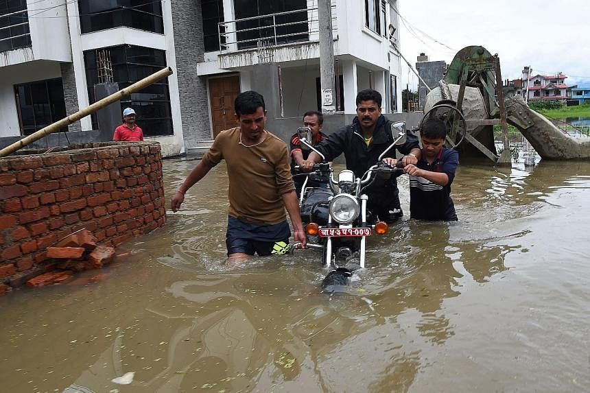 A flooded street in Patan, near Kathmandu, yesterday. Rescuers are searching for scores buried in submerged villages as thousands flee for higher ground.