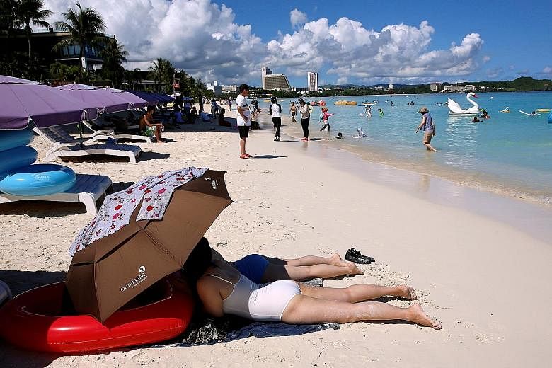 Left: Tourists sunbathing in the Tumon district on the island of Guam, a US Pacific territory, last Saturday. Some 85 per cent of its tourists come from South Korea and Japan. Above: Guam Governor Eddie Calvo speaking to the media at the government c