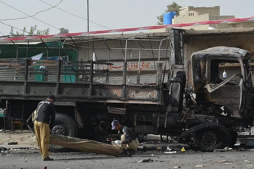 Pakistani security officials inspecting the scene of the explosion at a bus stop in Quetta yesterday.