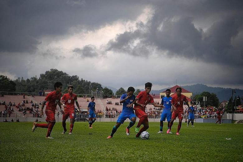 Under a stormy sky, Muhaiman Suhaimi (No. 7) attempts to gain possession during the 2-0 defeat by Myanmar at the Selayang Stadium yesterday. The Young Lions now face a crunch match against hosts Malaysia.