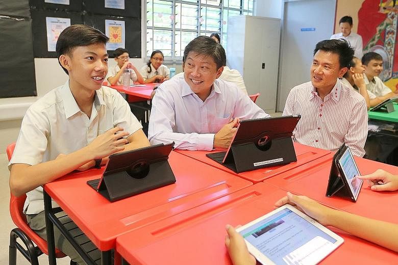 Education Minister (Schools) Ng Chee Meng (centre) checking out the use of the Singapore Student Learning Space with Secondary 3 student Jannsen Low Yu Heng and classmates at Admiralty Secondary School yesterday, accompanied by the principal Toh Thia