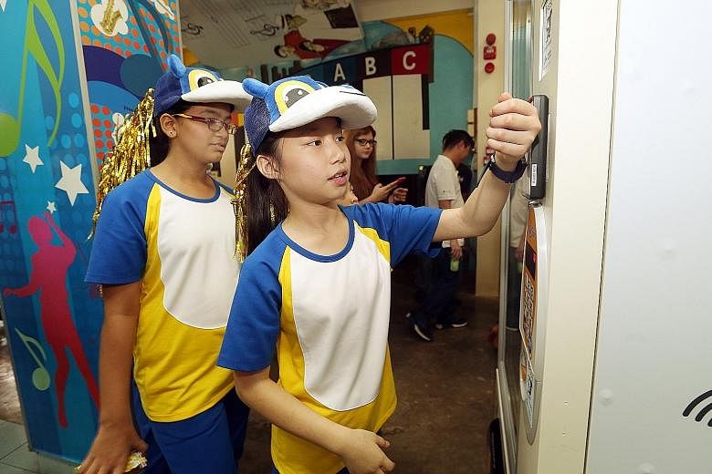 Pupil Vernice Lim, 11, using her smartwatch at a vending machine to pay for a drink at Admiralty Primary yesterday.