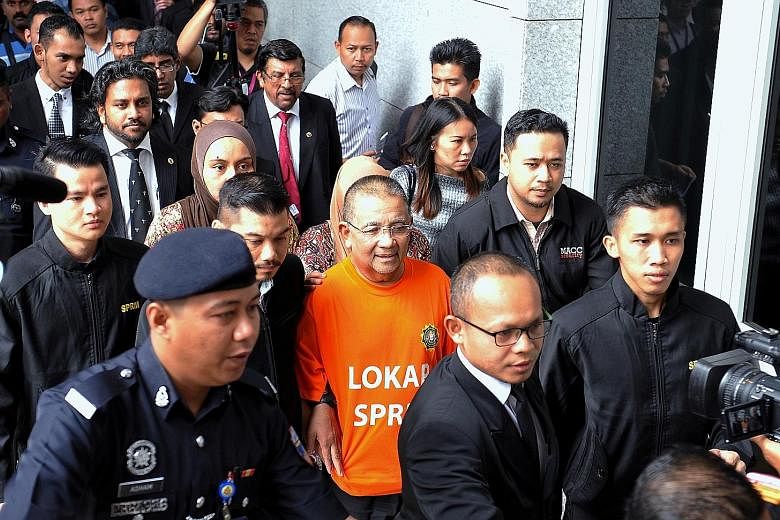 Mohd Isa Samad (in orange), who was appointed Felda chief in 2011 but replaced in January this year, arriving at the Putrajaya court complex yesterday for his remand hearing. The probe allegedly involved the land agency overpaying by hundreds of mill