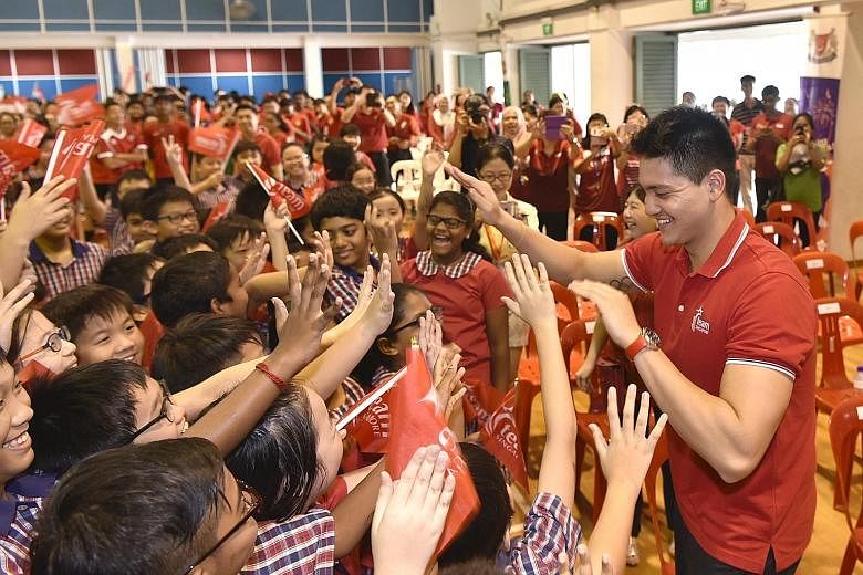 Pupils at Yuhua Primary School relishing the chance to exchange high-fives with Olympic champion Joseph Schooling yesterday.