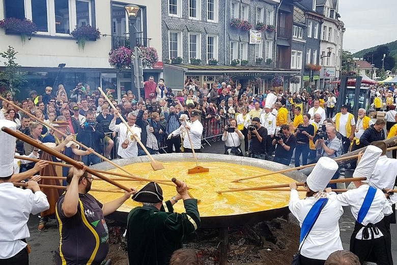 Members of The World Fraternity of Knights of the Giant Omelette, created in 1973, honouring their 22-year-old tradition of making a giant omelette despite an egg contamination scare. They cooked 10,000 eggs in a 4m-wide pan over an open fire as musi