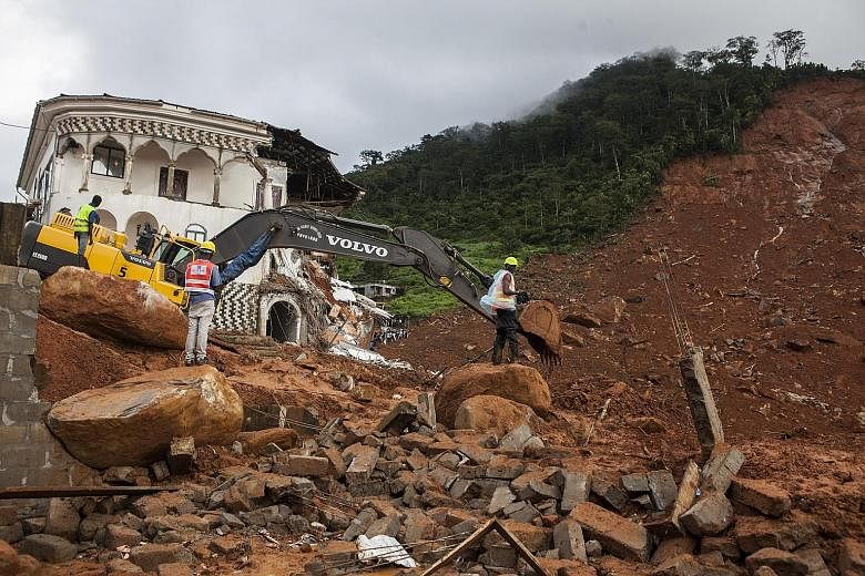 Workers move debris before searching for trapped bodies in the neighbourhood of SS Camp, where homes were destroyed by a mudslide in Freetown, Sierra Leone, on Monday. Residents of the poor communities built into the capital city's unstable hillsides