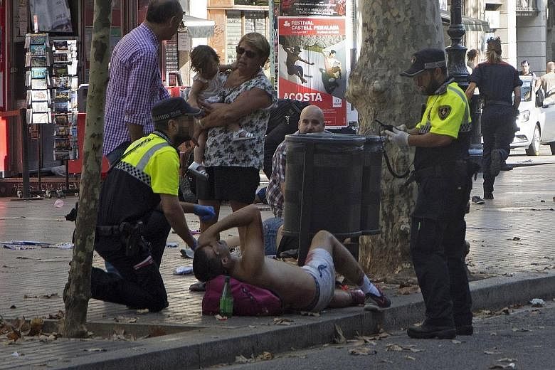 The aftermath after the van crashed into pedestrians in the popular tourist area of Las Ramblas in Barcelona yesterday. At least one person died in the incident, which Barcelona police said was a terrorist attack. Police officers attending to one of 
