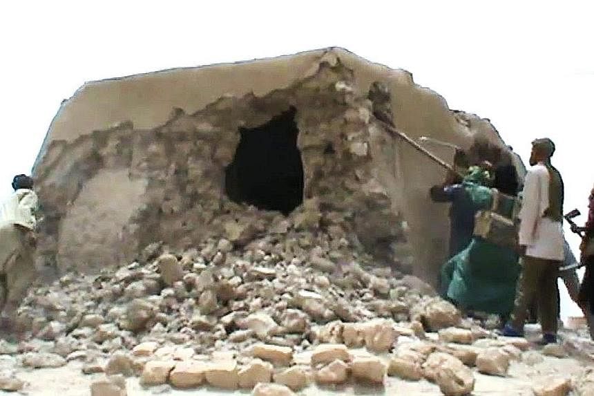 Left: The 15th-century mosque in Mali that was destroyed has been restored with the help of foreign donors. Above: A still from a video taken on July 1, 2012, showing Islamist militants destroying one of the nine shrines.