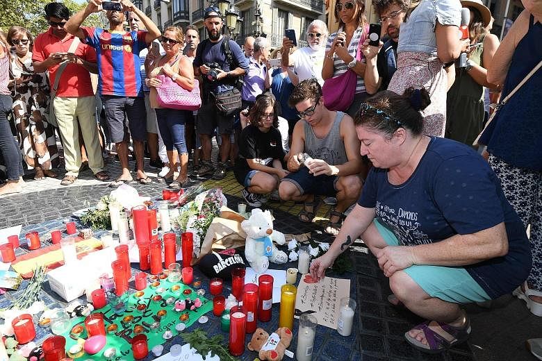 People paying their respects to the victims of the van attack at a makeshift memorial set up on the Las Ramblas promenade in Barcelona yesterday. The attack killed at least 13 people and injured more than 100 others.