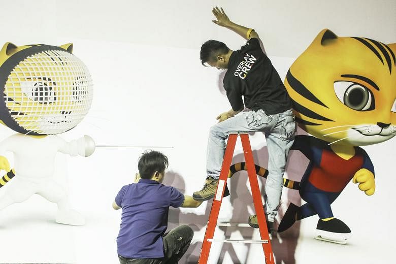 Workers putting up a SEA Games billboard in the main media centre in Kuala Lumpur last week, before the start of the sporting event today. The host nation gets to decide what sports to drop and include and, in recent years, this leeway has become a t
