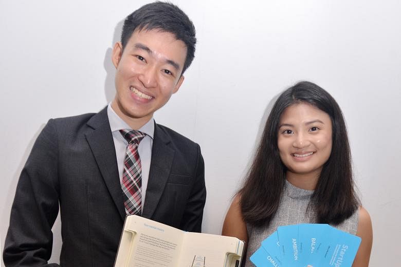 SMU students Ling Kai Tsi and Melissa Chia with a journal and cards that will be used in the Pathfinders programme.