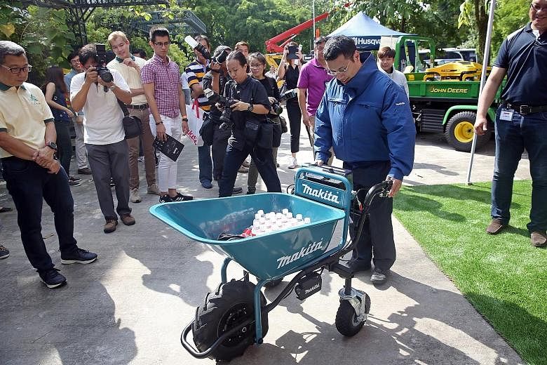 Mr Desmond Lee trying his hand at a battery-powered wheelbarrow while wearing a cordless fan jacket at the Landscape Industry Fair in HortPark yesterday. Both items are equipment used in landscaping work.