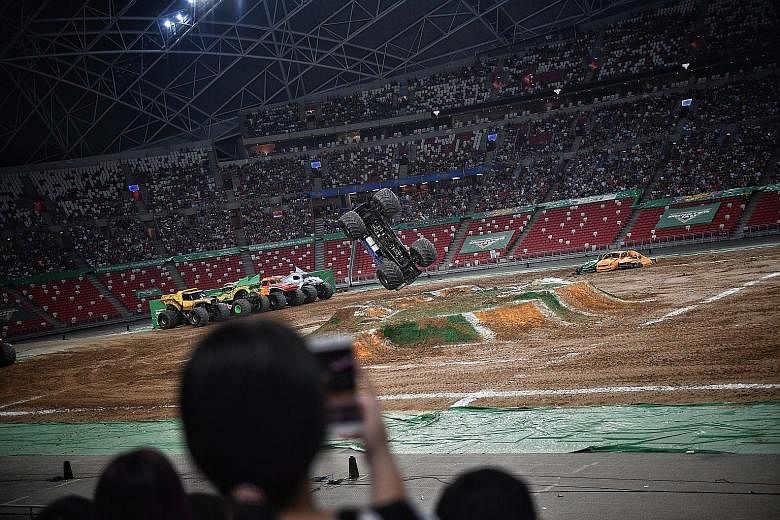 Fans (left) being thrilled by jaw-dropping feats (far left) at Monster Jam Singapore yesterday at the National Stadium. Drivers carried out jumps, doughnuts (where the truck spins in circles) and flip-overs, with the truck's roof on the ground.