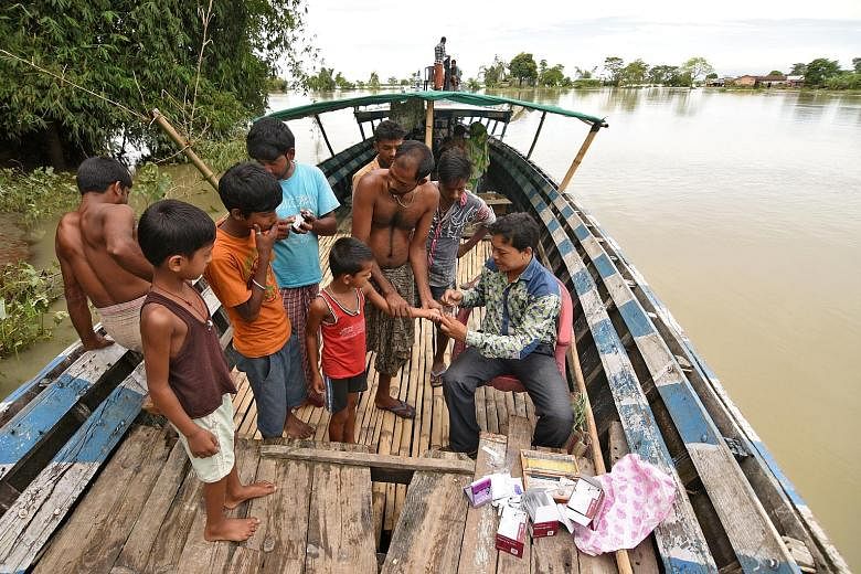 A health official collecting blood samples from boys in a flooded village in Morigaon district in the north-eastern state of Assam, India, on Friday. The latest floods and landslides in the subcontinent began in the second week of the month as the an