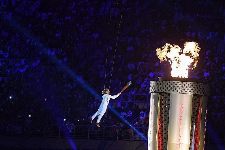 Malaysian diver Nur Dhabitah Sabri being hoisted up in the air to light the cauldron during the SEA Games opening ceremony at the National Stadium in Kuala Lumpur last night. The biennial Games were officially opened by the King of Malaysia, Sultan M