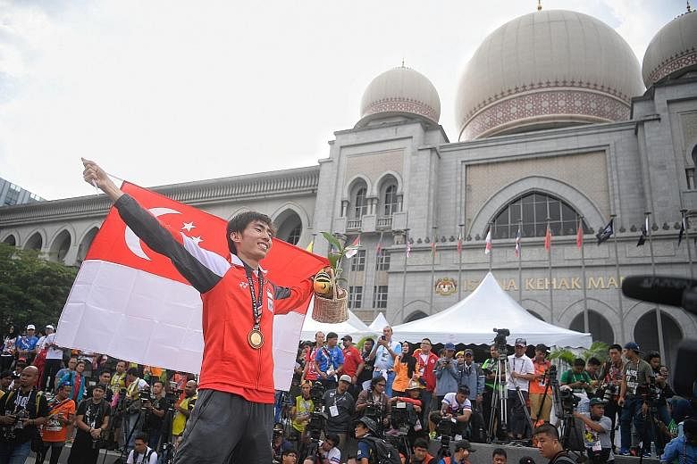 Singapore marathoner Soh Rui Yong celebrating his victory on the podium in front of the Istana Kehakiman, in Putrajaya, yesterday. The Republic's women's water polo team also picked up a silver medal.