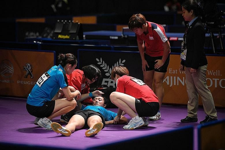 Feng Tianwei receives medical attention after falling and hitting her head during the women's doubles final yesterday. She and Yu Mengyu beat defending champions Zhou Yihan and Lin Ye 11-8, 11-9, 11-13, 8-11, 11-6.