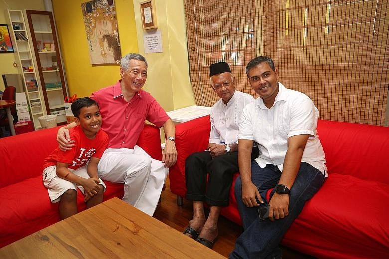 Prime Minister Lee Hsien Loong with (from left) nine-year-old Adam Zafran Aziz, Mr Ahmad Azali, 79, and Mr Aziz Ahmad, 42. Mr Lee said: "This is the Singapore of the last half century: Ahmad, a gardener; Aziz, a pharmaceu- tical engineer; and Adam, (