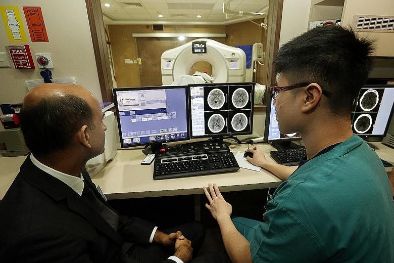 Consultant Jai Rao and radiographer Douglas Tien from the National Neuroscience Institute discussing a case as a patient undergoes a computed tomography brain scan. The institute and Nanyang Technological University are in a tie-up that will see medi