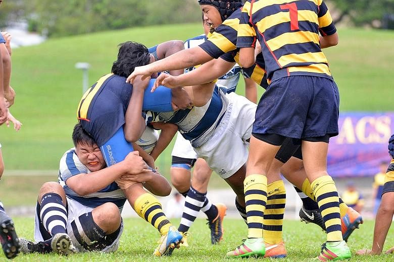 St Andrew's Secondary School players trying to stop the charge of Anglo-Chinese School (Independent) during the Schools National C Division rugby final[…], which the latter won 25-10.